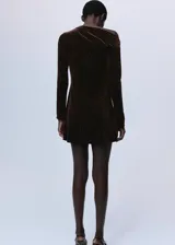Vestido corto de terciopelo con brillos, diseño entallado, cuello asimétrico y manga larga.