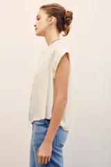 Camisa sin mangas de corte amplio y color fucsia, con cuello mao y cierre frontal de botones ocultos.