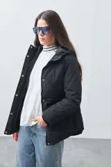 Campera matelasé color negro con capucha, cierre frontal con botones a presión y bolsillos frontales con cierre.
