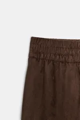 Pantalón de tiro alto con diseño de pierna ancha, confeccionado en tejido con efecto ante. Cuenta con cintura elástica y bolsillos laterales ocultos en la costura.