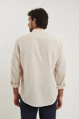 Camisa de cuello mao y manga larga, confeccionada en una mezcla de lino y algodón. Presenta un diseño de corte recto con botones en tono natural y un bolsillo pequeño en el pecho.