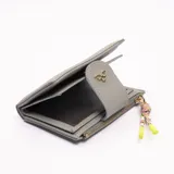 Billetera gris con cierre de broche y cierre de cremallera, con adorno de borla de colores.