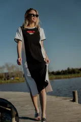 Vestido largo de algodón color blanco con panel central negro y bordado geométrico en el pecho. Tiene corte de remera, cuello redondo y tajos laterales.