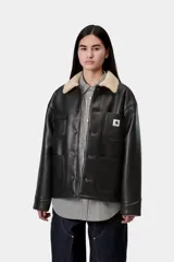 Chaqueta de trabajo Carhartt WIP modelo Michigan Shepton, color negro, confeccionada en piel sintética con cuello y forro de corderito sintético en tono tostado. Presenta cierre frontal de botones, cuatro bolsillos delanteros de parche (uno con solapa) y etiqueta cuadrada con el logo de la marca.