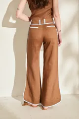 Pantalón azul marino de corte wide leg con detalles en tono marrón tostado en la cintura, bolsillos y bordes laterales, cuenta con trabillas para cinturón y cierre frontal.