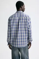 Camisa de manga larga con ajuste relajado, cuello inglés y un bolsillo aplicado en el pecho. Presenta cierre frontal de botones y bajo redondeado.