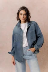 Camisa de denim de lavado medio con calce oversize, cuello camisero, cierre frontal con botones y bolsillos aplicados en el frente.
