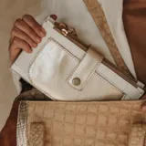 Billetera de cuero color blanco y dorado con textura croco. Tiene bolsillo en el frente, dos bolsillos con cierre a sus extremos y dos bolsillos para tarjetas en su interior.