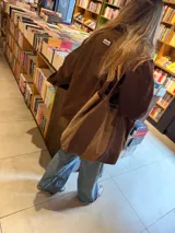 Bolso tipo shopper de gran tamaño, confeccionado en una combinación de cuero y gamuza en tonos marrones. Presenta un diseño bicolor con paneles verticales, doble asa de hombro y bolsillo interior.