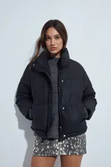 Campera puffer de nylon color marrón oscuro, con cuello alto, cierre frontal y puños elásticos. Diseño acolchado de volumen ligero.