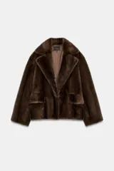 Abrigo corto de Zara con diseño de efecto pelo, cuello de solapa con muescas, manga larga y bolsillos frontales con solapa. Cuenta con forro interior a tono y cierre frontal con botón.