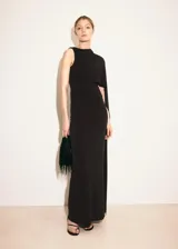 Vestido largo negro de corte entallado y diseño asimétrico, sin mangas, con detalle de capa en el cuello y fruncidos laterales.
