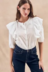 Blusa blanca de algodón con bordado floral, cuello redondo, manga corta con volados y cierre frontal con botones.