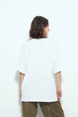 Remera blanca de manga corta con calce relajado y cuello a la base. Presenta un estampado frontal pequeño y una estampa protagonista en la espalda con el texto "Rocky Mountain National Park" y un paisaje de montañas y árboles.