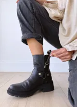 Bota corta negra de cuero, con caña media, hebilla lateral y suela track.