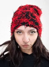 Gorro tipo beanie de tejido desmechado con textura irregular, combinando fibras en color rojo y negro.
