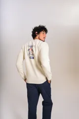 Buzo de cuello redondo color crudo, con detalle de logo bordado en el pecho, mangas largas y puños elastizados.