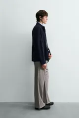 Sobrecamisa de hombre, color azul marino oscuro, confeccionada en piel con acabado ante. Presenta cuello solapa, manga larga con puños abotonados, un bolsillo de parche en el pecho y cierre frontal de botones.