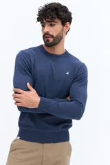 Sweater de punto color azul melange, con escote redondo, manga larga y puños y ruedo acanalados. Presenta un pequeño logo bordado en el pecho.