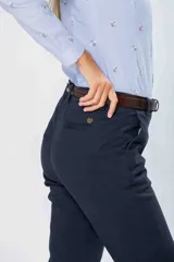 Pantalón de gabardina gris con corte clásico, bolsillos laterales y traseros, y cierre frontal con botón y cremallera. Incluye cinturón fino de cuero marrón con hebilla dorada.