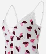 Camisón corto de microfibra color blanco con estampado de corazones en tonos rosado y bordó. Presenta breteles finos regulables, escote en V realzado con puntilla blanca y terminación de encaje en el ruedo.
