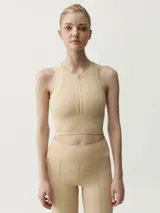 Top deportivo color beige, de cuello redondo con cierre frontal parcial y diseño ajustado.