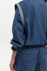 Jean wide leg de denim azul con elástico en la cintura, cordón ajustable y bordados decorativos en los laterales.