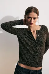 Chaqueta de punto de manga larga y cuello redondo, con cierre frontal de botones y estampado animal print en tonos marrones y negros.