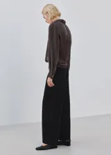 Pantalón de jean negro de corte recto y tiro medio, con cierre de botón y cremallera, y bolsillos laterales y traseros.