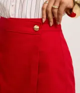 Short pollera de cintura alta confeccionado en sarga de algodón, con diseño de traspase tipo sobre y detalle de botón dorado en el frente.