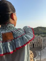 Camisa a rayas verticales blancas y verdes con cuello alto fruncido y volados con borde rojo en cuello, mangas y pecho.