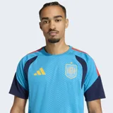 Camiseta de entrenamiento de fútbol Adidas para hombre, color celeste vibrante con textura de micro-puntos. Presenta detalles en azul marino en las mangas y hombros, con franjas en rojo y amarillo en la parte superior de los hombros. Incluye el escudo de la selección española y el logo de Adidas en amarillo.