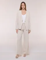 Blazer de sastrería color beige, sin solapas, con cuello en V profundo y cierre frontal de un único botón circular metálico en contraste.