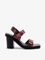 Sandalias de cuero vacuno color bordó con tiras ajustables con hebilla y detalles de gemelos de bronce. Poseen plataforma de EVA y taco alto de madera.