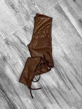 Pantalón chupín de cuero sintético color chocolate con aberturas laterales con cordones cruzados.