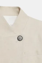 Blazer corto de lino color beige, con cuello redondo y cierre frontal cruzado con un botón negro.