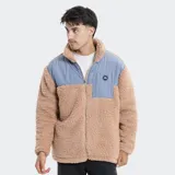 Campera de polar tipo sherpa en color beige, con paneles superiores en color azul grisáceo. Presenta cuello alto, cierre frontal completo y un bolsillo en el pecho con cierre y logo de la marca.
