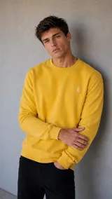 Buzo de cuello redondo en color amarillo, con diseño de calce clásico y puños acanalados. Presenta un pequeño logo bordado en el pecho.