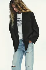 Blazer negro de corte oversize, con cuello solapa, escote pico, manga larga con hombreras y forro interior. Presenta bolsillos con solapa delanteros y bolsillo de vivo en el pecho.