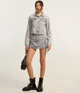 Campera corta de jean color negro con cuello inglés, abotonadura frontal, bolsillos tipo parche con solapa en el pecho y mangas largas.