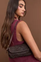 Cartera de hombro de cuero chocolate con diseño entrelazado, cierre de solapa con doble botón magnético y correa ajustable.