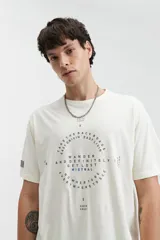 Remera de manga corta color crema, con ajuste regular y escote redondo. Presenta un estampado frontal con lettering en forma circular y la palabra "MISTRAL" en azul.