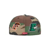 Gorra tipo snapback de Supreme con diseño de camuflaje woodland. Presenta bordados frontales con letras y un tigre, además de un logo lateral de un águila y el logo de New Era.