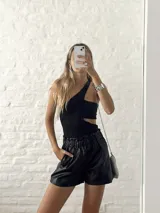 Top negro asimétrico con un solo hombro, corte en la cintura y abertura lateral.