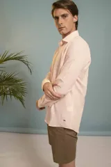 Camisa de manga larga en color salmón con estampado de pequeños motivos geométricos oscuros, cuello clásico y cierre frontal con botones.