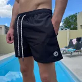 Short de baño negro con cintura elástica y cordón ajustable bicolor. Presenta un parche circular con logo en la parte inferior de la pierna.