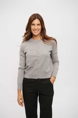 Saco de tejido de punto gris claro, de manga larga y cuello redondo, con cierre frontal de botones pequeños.