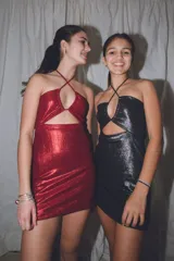 Vestido corto ajustado con acabado brillante, color rojo metálico. Presenta un escote halter con tiras cruzadas y un corte cut-out en la zona del abdomen.