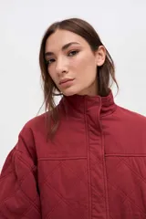 Campera bomber de gabardina con diseño capitoneado, cuello alto, cierre frontal con botones a presión ocultos y mangas abullonadas con puños elásticos.