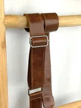 Correa ajustable para cartera confeccionada en cuero marrón con costuras a la vista y herrajes metálicos plateados.